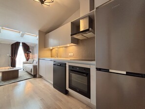 Eine moderne Küche mit Einbaugeräten, ein Essbereich mit einer Couch und Blick zum Wohnzimmer.