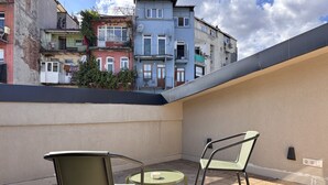 A rooftop terrace with two chairs and a small table, overlooking a row of colorful buildings. - Penthouse Suite with Private Terrace (Istanbul)