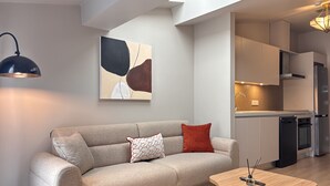 A modern living room with a sofa, a coffee table, and a kitchen in the background. - Penthouse Suite with Private Terrace (Istanbul)