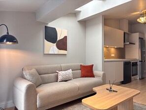 Ein modernes Wohnzimmer mit einer Couch, einem Couchtisch und einer Küche im Hintergrund.