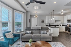A modern living room with a gray sofa, a teal armchair, and a coffee table with a plant.