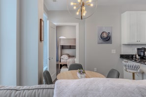 A modern bedroom with a bed, bedside table, and a view into the adjacent room.