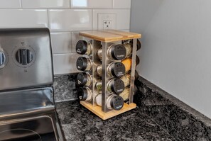 A kitchen with a stainless steel stove, a spice rack with labeled containers, and a granite countertop.