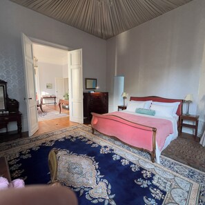 Ein Schlafzimmer mit einem großen Bett, einem Holzkonsolenmöbel, einem Nachttisch und einem Spiegel an der Wand.
