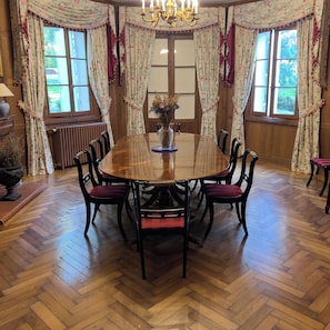 Ein Esszimmer mit einem großen Holztisch, sechs Stühlen und einer Vase mit Trockenblumen.