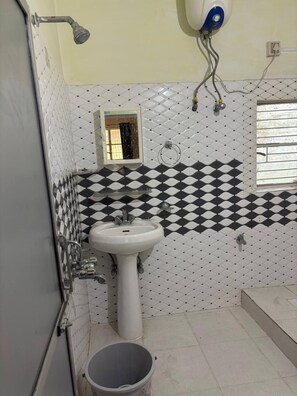 A bathroom with a white sink, a mirror, a shower, and a toilet.