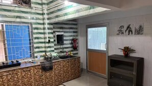 A kitchen with a patterned backsplash, a window with a blue grid, a sink, and a small cabinet.