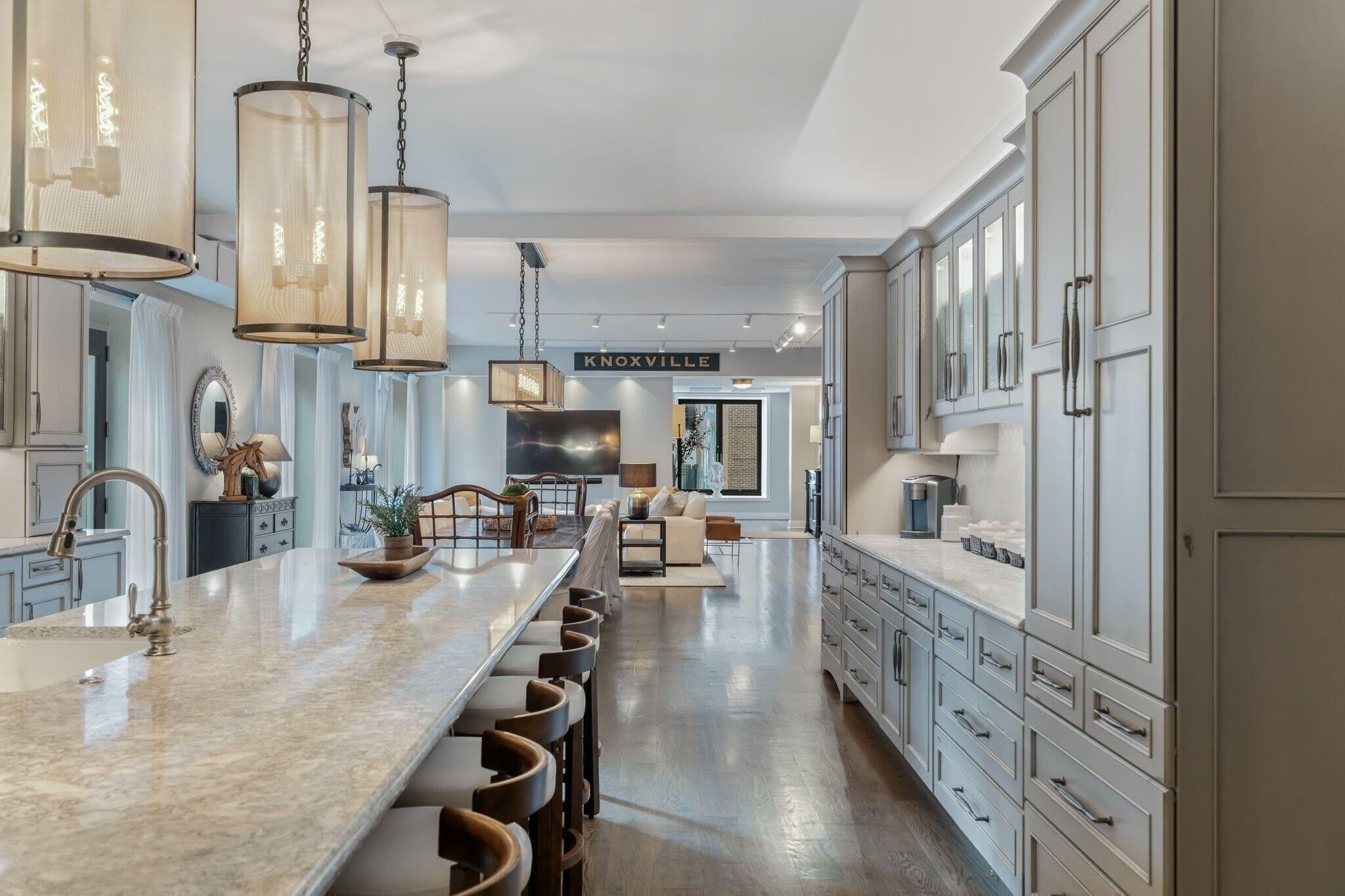 A spacious kitchen with a long island, bar stools, and a large cabinet area.