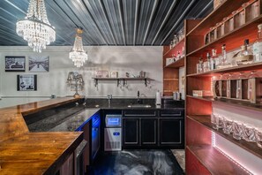 A bar area with a wooden counter, a digital display, and a chandelier. - Historic Loft, Downtown Knoxville, Market Square (Knoxville)