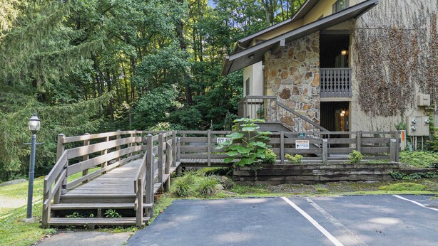 A wooden bridge leading to a stone building with a balcony, surrounded by greenery. - 3BR Condo Near Ober Mountain & Downtown Gatlinburg (Gatlinburg)