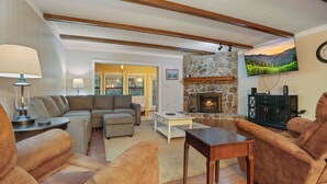 A living room with a fireplace, sofas, a coffee table, and a television mounted on the wall. - 3BR Condo Near Ober Mountain & Downtown Gatlinburg (Gatlinburg)