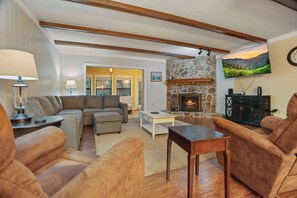 A living room with a fireplace, sofas, a coffee table, and a television mounted on the wall. - 3BR Condo Near Ober Mountain & Downtown Gatlinburg (Gatlinburg)