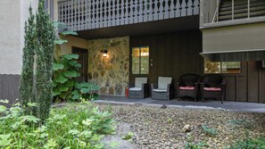 A building with a stone facade, outdoor seating area with wicker chairs, and a gravel pathway. - Bright Sunroom, Wooded Views, Ober Mountain Base (Gatlinburg)