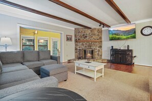 A living room with a sectional sofa, a fireplace, a flat-screen TV, and a clock on the wall. - Bright Sunroom, Wooded Views, Ober Mountain Base (Gatlinburg)