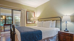 A bedroom with a bed, a nightstand, a mirror, and a window with curtains. - 3BR Condo Near Ober Mountain & Downtown Gatlinburg (Gatlinburg)