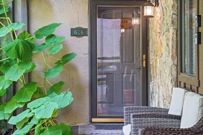 Une porte avec un panneau de verre, une plaque portant le numéro « 626 », et une chaise en osier à l’extérieur.