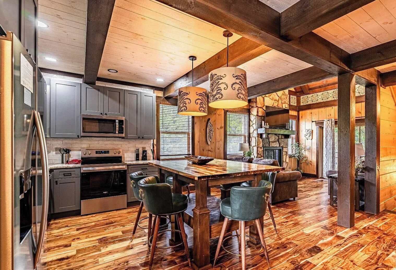 A spacious kitchen with a central island, bar stools, and a stone fireplace.