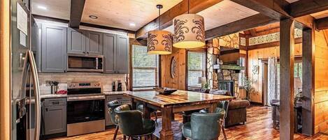 A spacious kitchen with a central island, bar stools, and a stone fireplace.