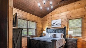 Ein Schlafzimmer einer Holzhütte mit Bett, Nachttischen und einer Kandelaber.