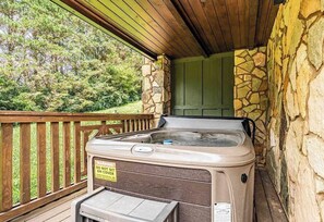 Ein Whirlpool auf einer Holzterrasse mit Steinmauern und einer grünen Tür.