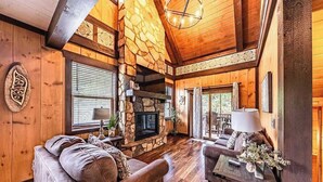 Ein gemütliches Blockhaus-Interieur mit Kamin aus Stein, Holzwänden und einer komfortablen Sitzecke.