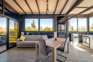 Uma cozinha moderna com área de refeições, grandes janelas e vista para árvores.