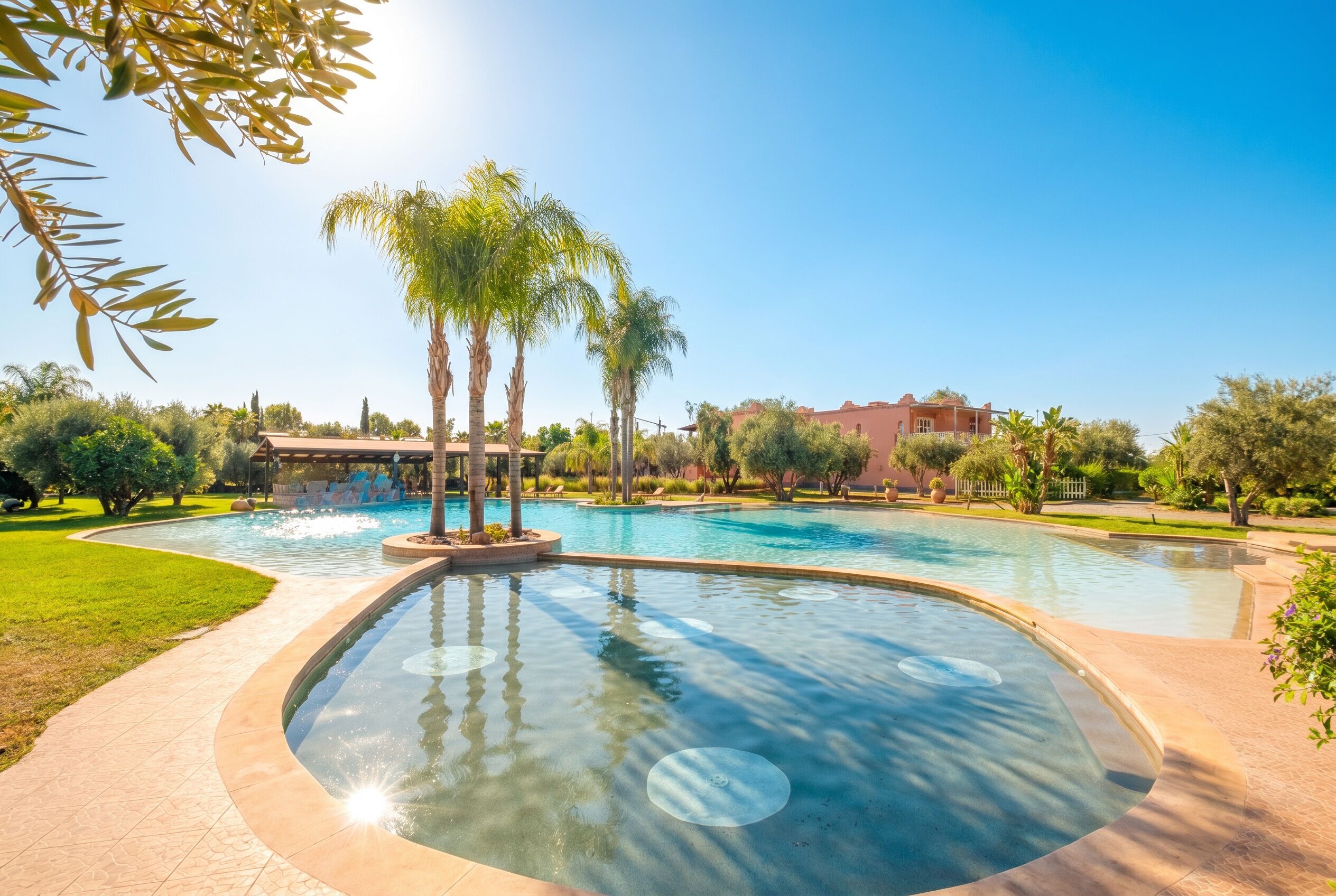 A large outdoor swimming pool with palm trees and a building in the background.
