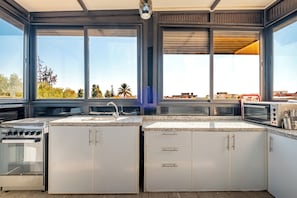 A modern kitchen with a large island, stainless steel appliances, and a view of the cityscape through large windows.