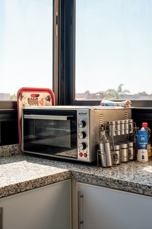 Uma cozinha com forno elétrico, utensílios de aço inoxidável e uma garrafa de água.