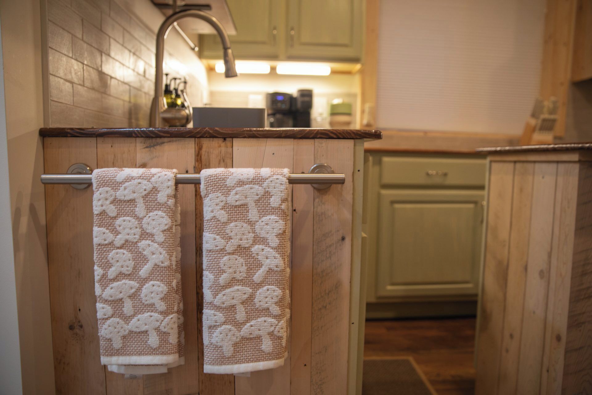 A kitchen with wooden cabinets, a stainless steel faucet, and two towels hanging on a towel rack.