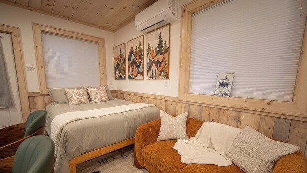Un dormitorio con una cama, un sofá, una silla y una ventana con persianas.