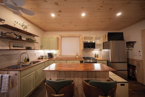 A kitchen with wooden cabinets, a central island, bar stools, a built-in oven, and a refrigerator.