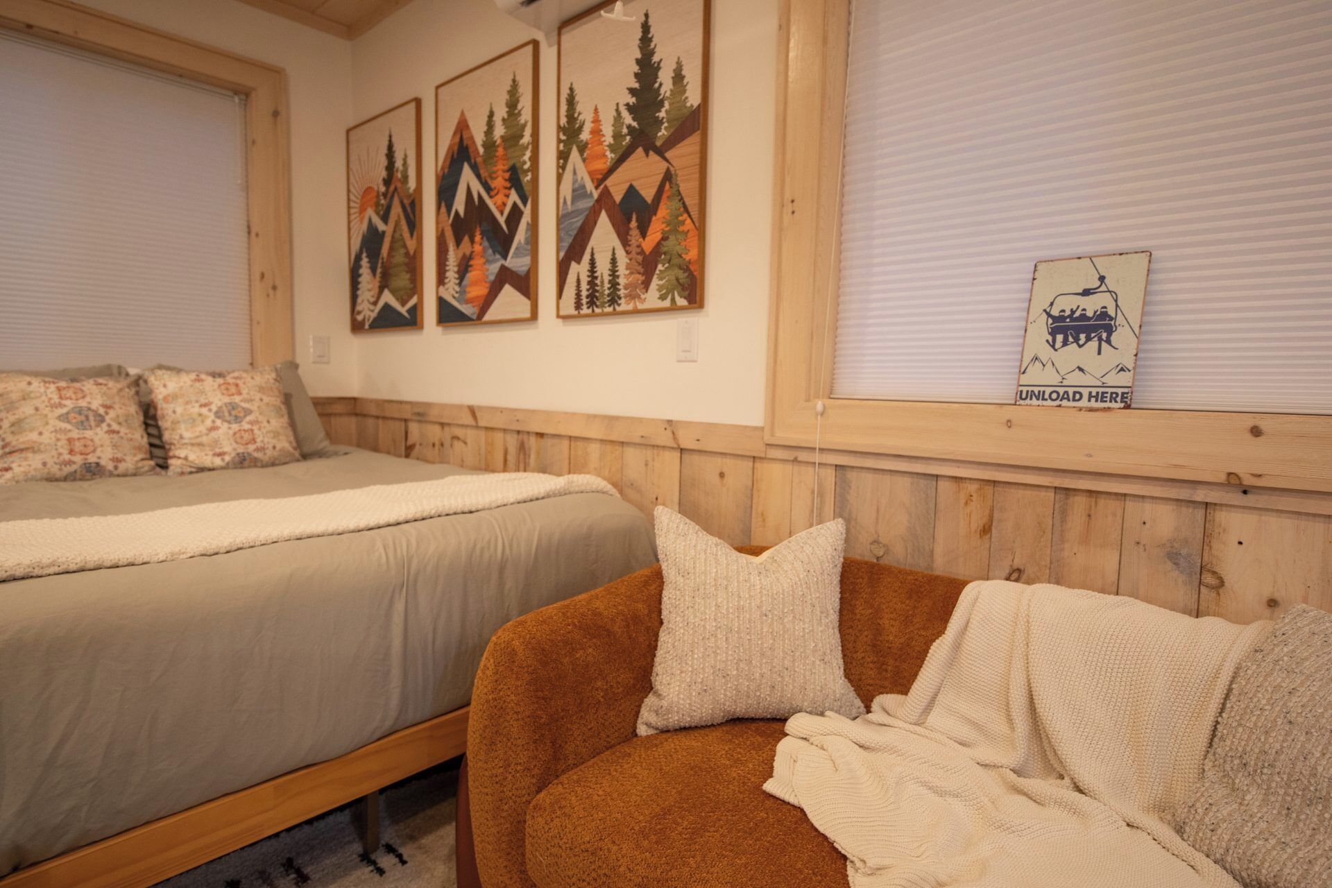 Una habitación con dos camas, un cabecero de madera y una pared con tres cuadros enmarcados.