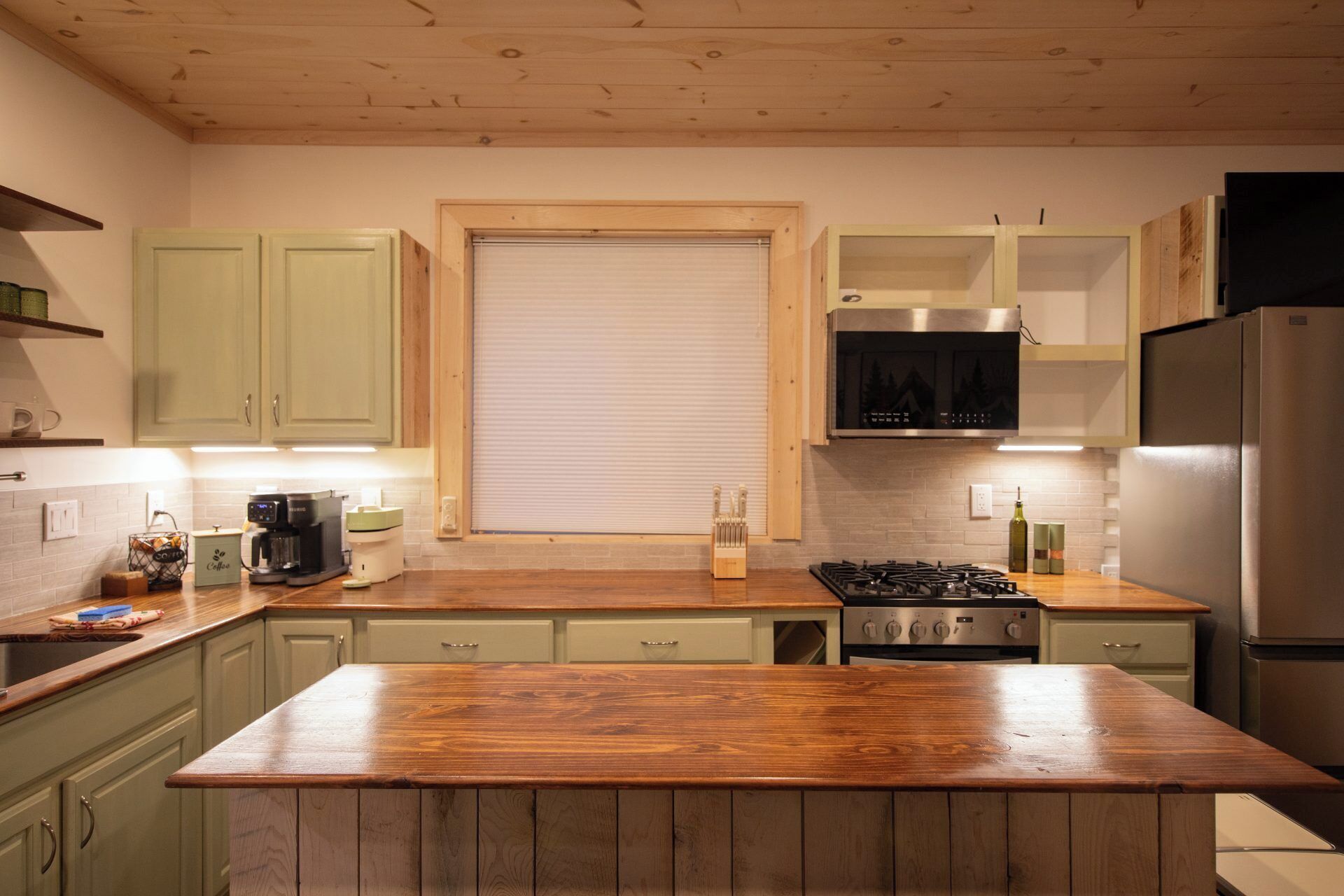 Una cocina con armarios de madera, una isla central, una estufa y un refrigerador.