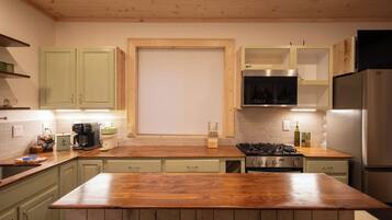 Una cocina con armarios de madera, una isla central, una estufa y un refrigerador.