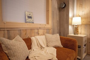 A cozy room with a wooden headboard, a lamp on a bedside table, and a framed picture on the wall.