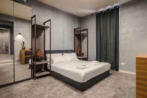 Un dormitorio moderno con una cama grande, un espejo y una cortina oscura.