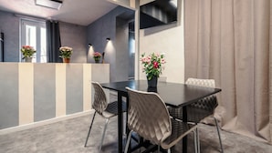 A modern dining area with a black table, two chairs, and a potted plant. - Termini Jacuzzi Suite (Roma)