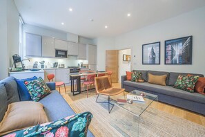 Ein modernes Wohnzimmer mit Sofa, Couchtisch und Essbereich mit Stühlen und Tisch.