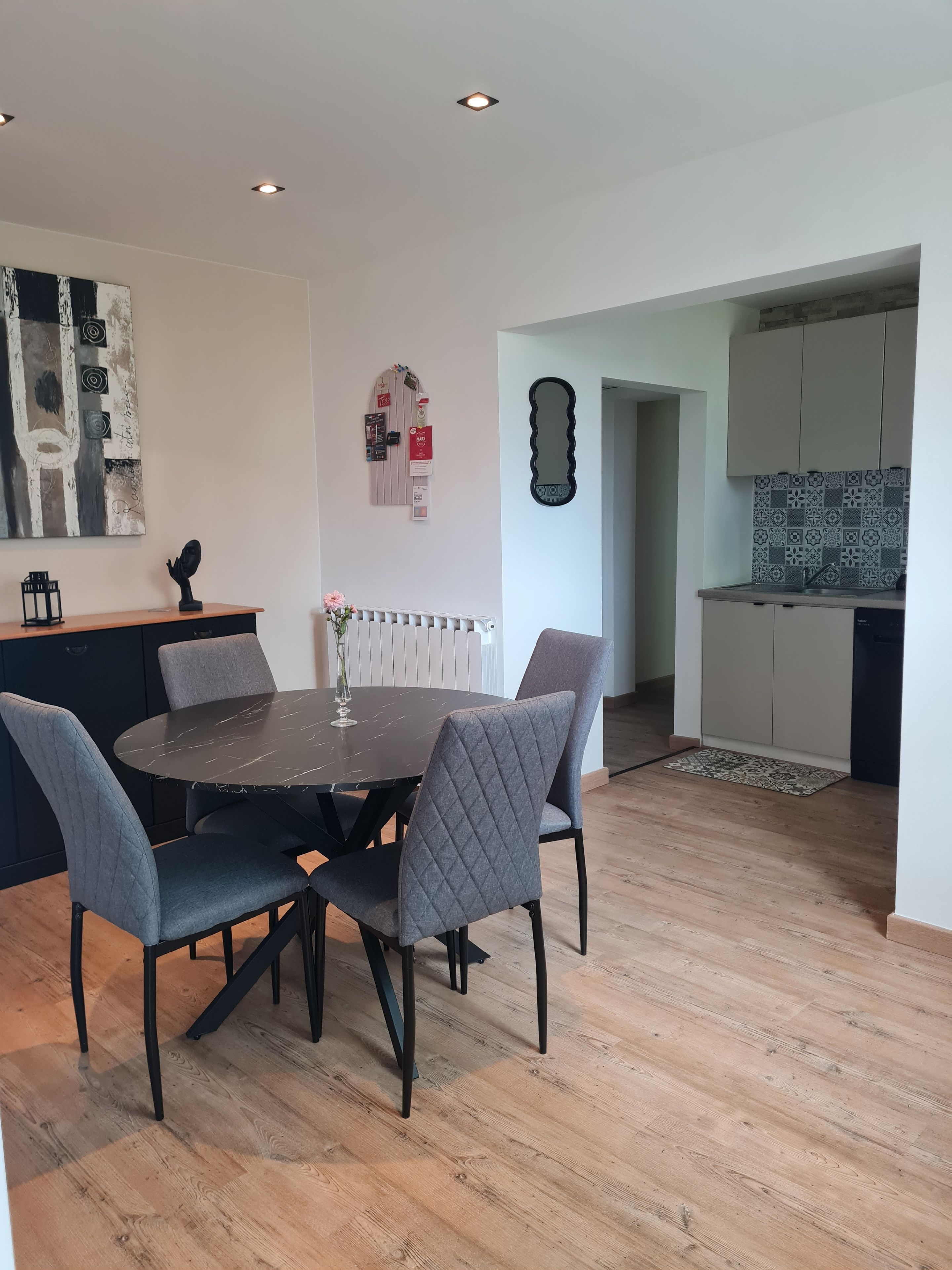 A modern kitchen with a dining area featuring a round table and grey upholstered chairs.