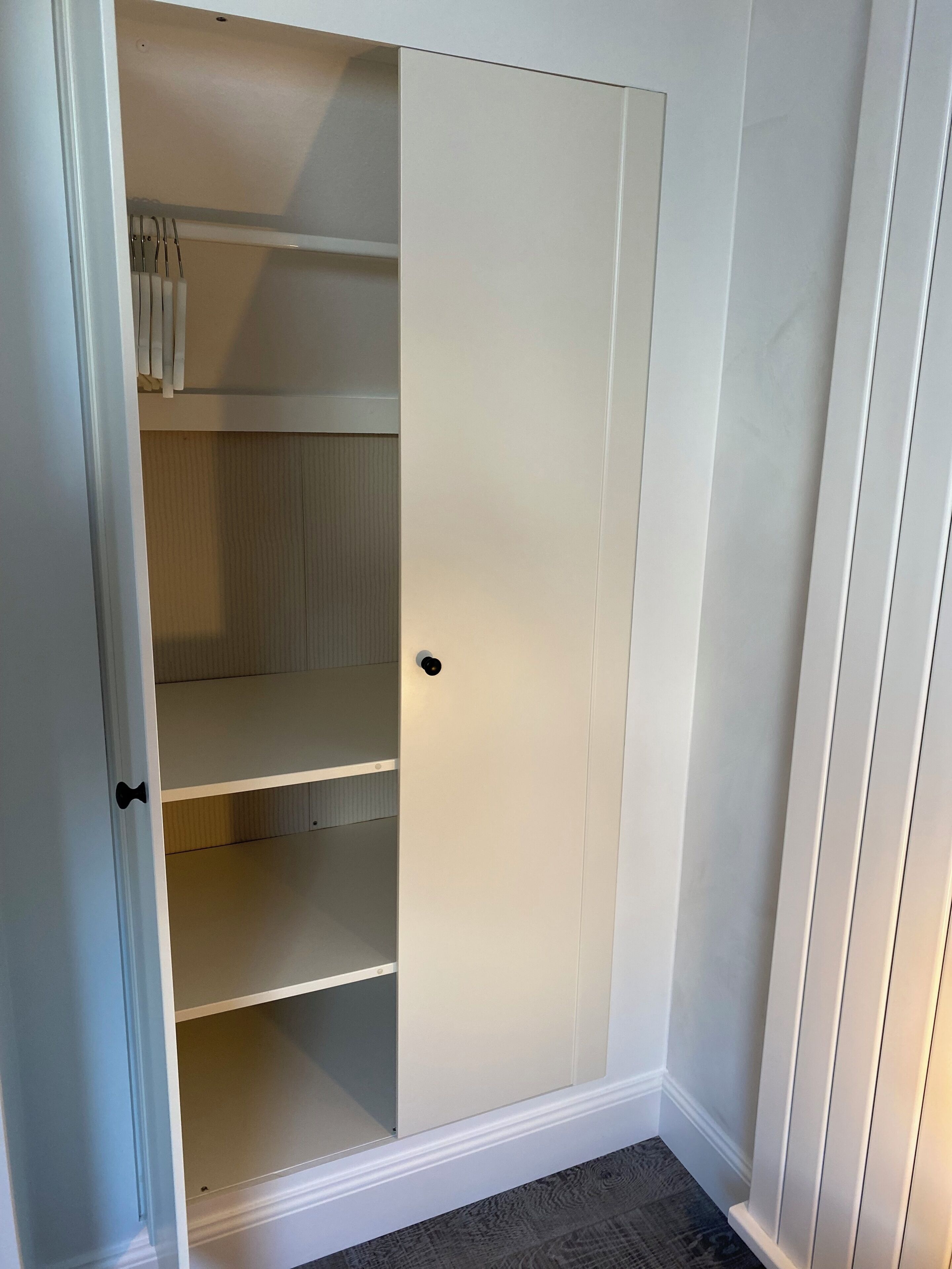 A white closet with multiple shelves and a door.