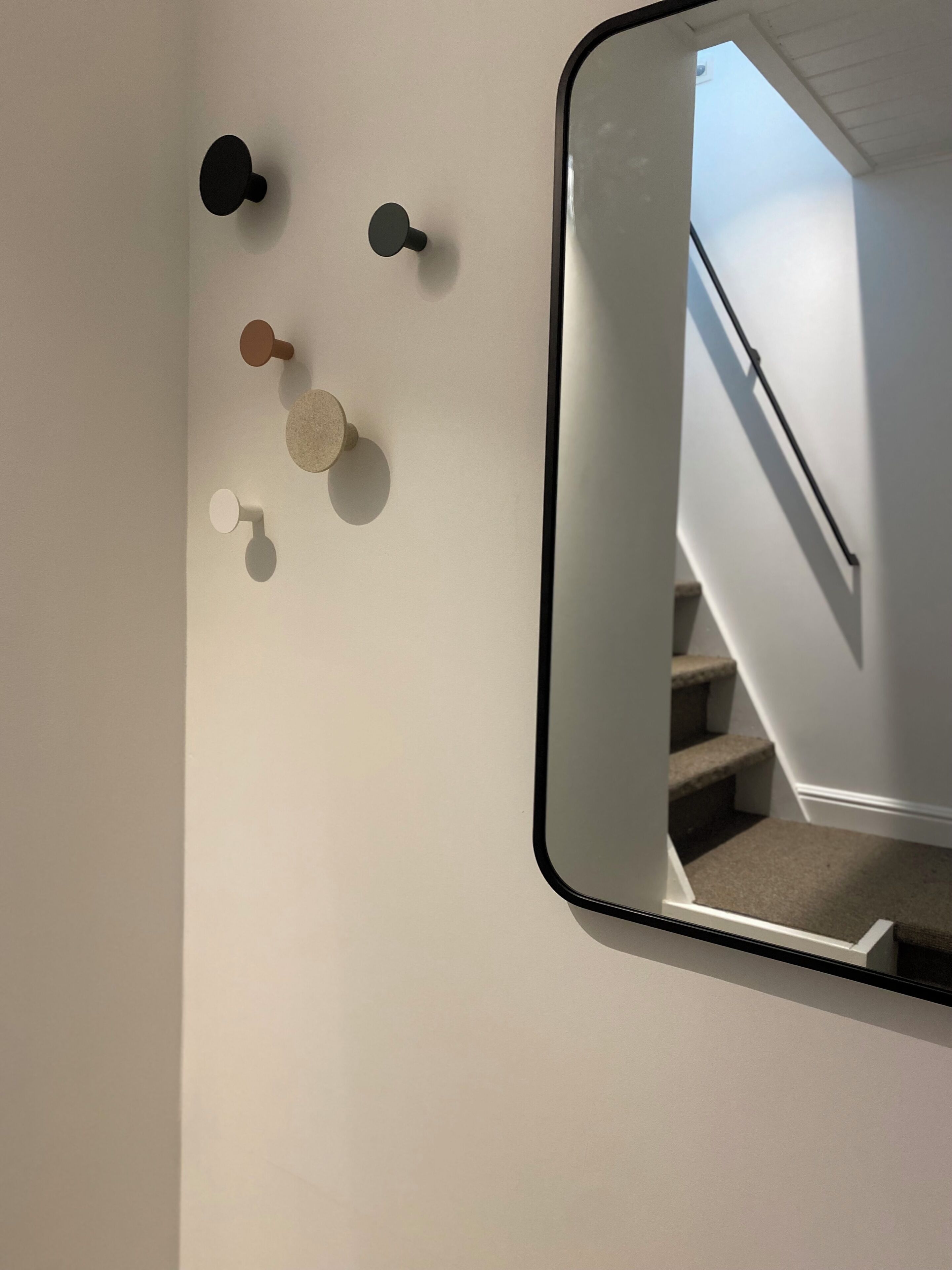 A wall with a mirror reflecting a staircase.