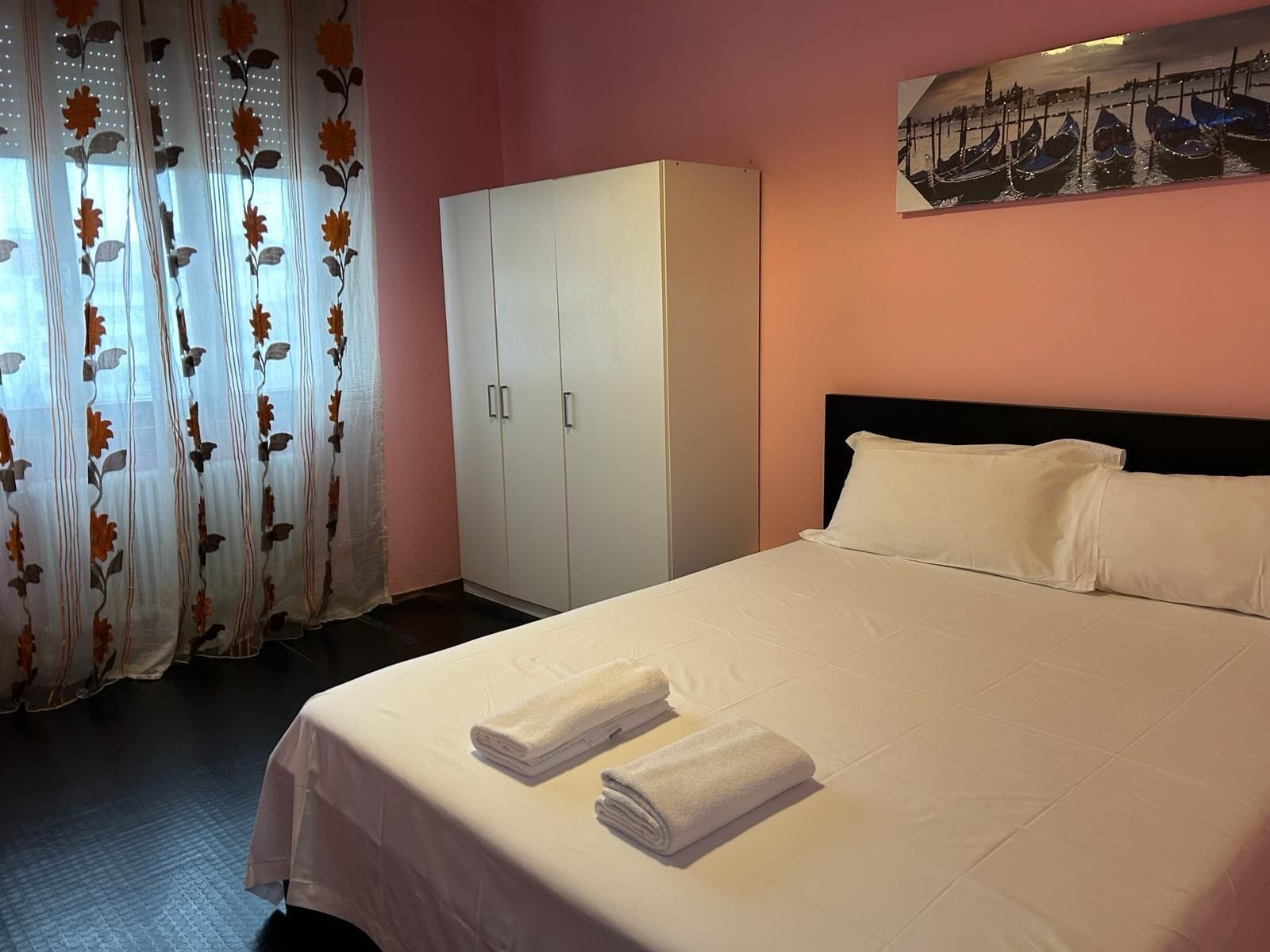 Ein Hotelzimmer mit einem Bett, einem Kleiderschrank und einem Gemälde an der Wand.