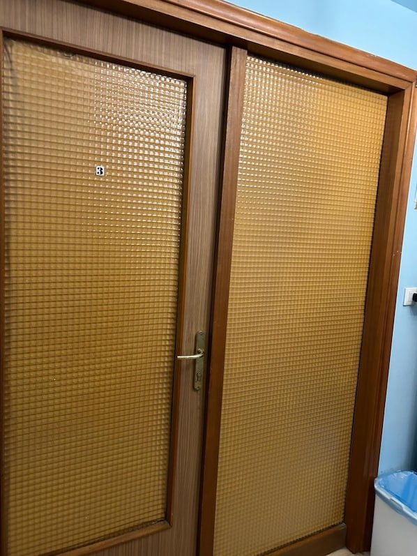Ein Holzschrank mit einer Tür aus strukturiertem Glas, einem sichtbaren Griff und einem kleinen Aufkleber mit der Zahl 3.