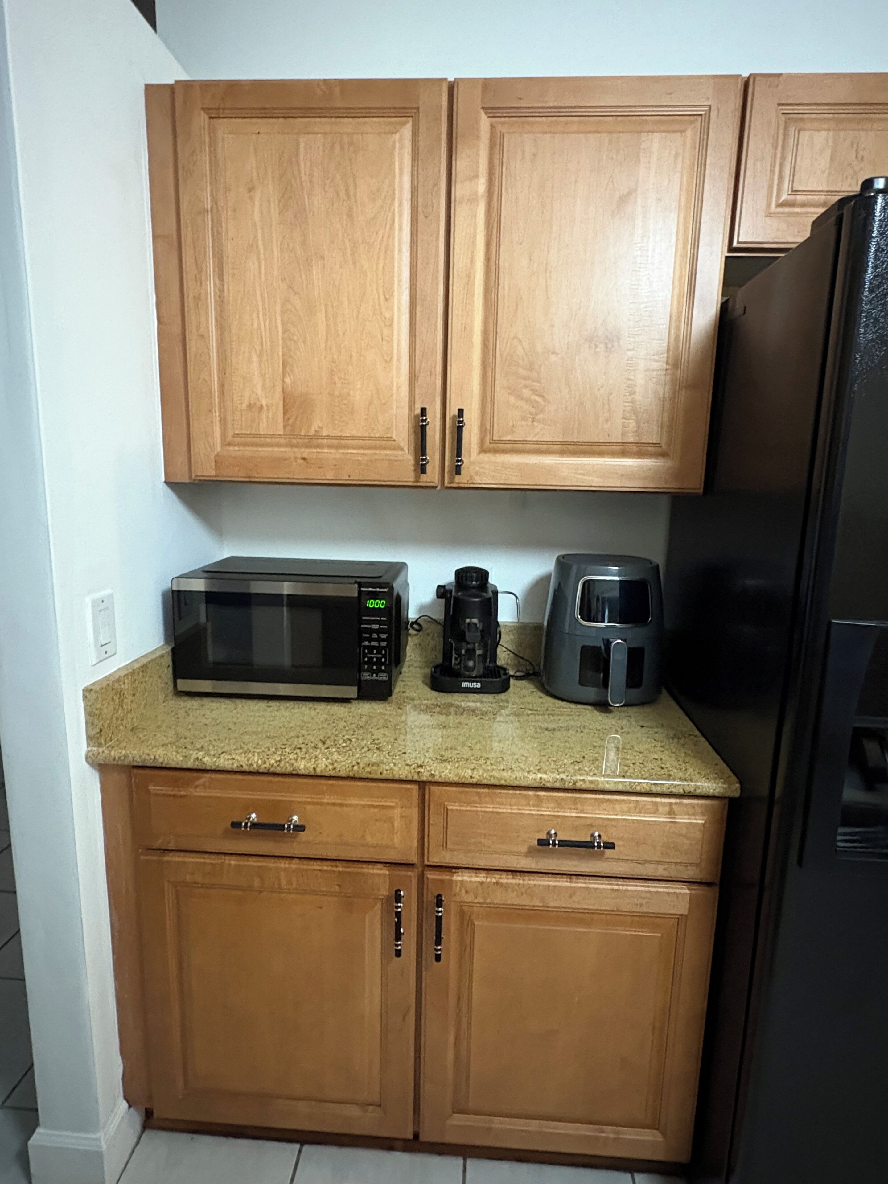 A kitchen with wooden cabinets, a microwave, a coffee maker, and a toaster.