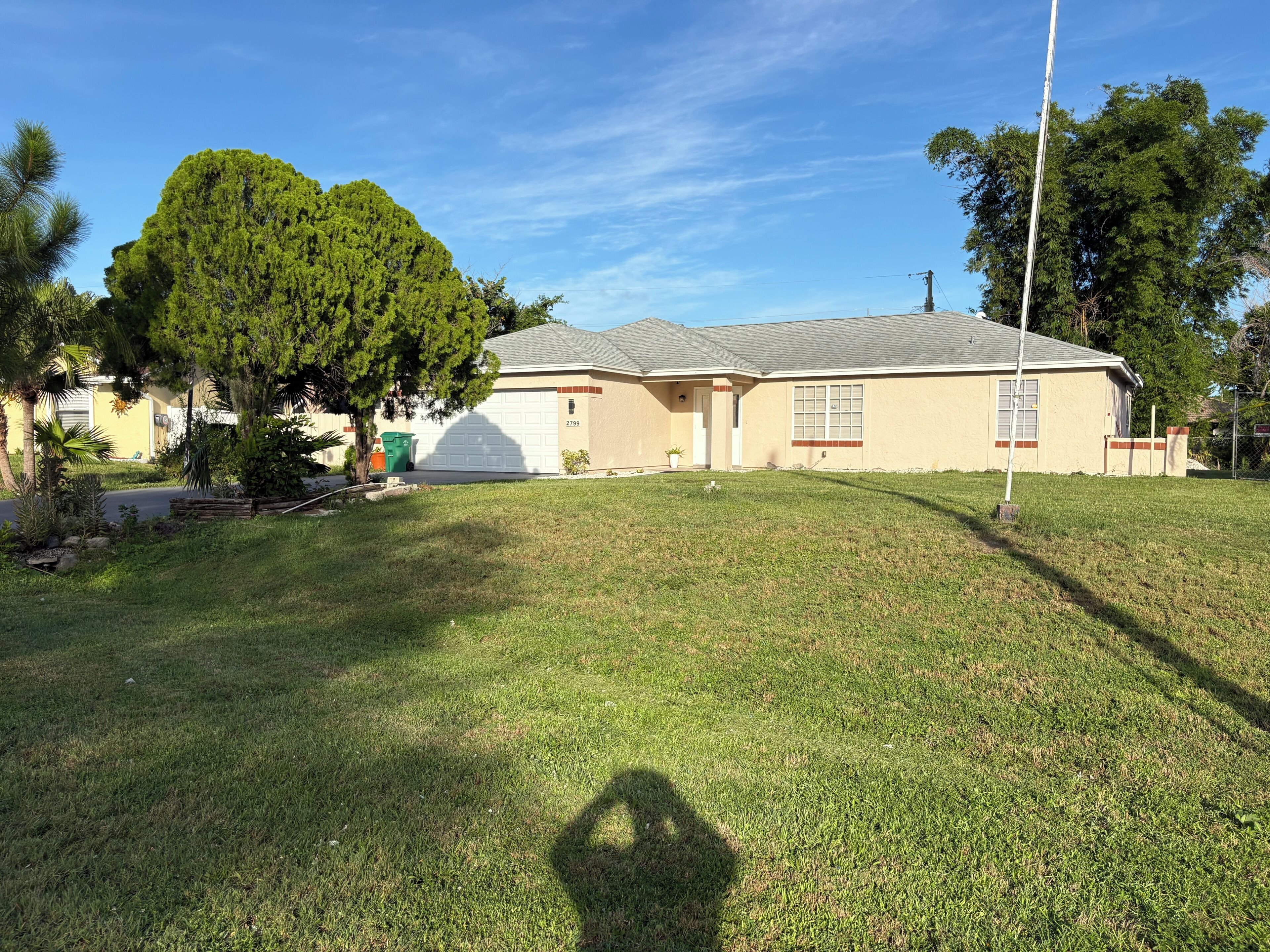 A residential house with a garage, a well-maintained lawn, and a large tree in front.