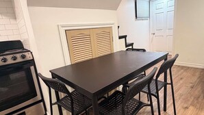 A kitchen with a dark wooden table and chairs, a stove, and a window with blinds. - Room to Stay in Niagara Falls (Niagara Falls)