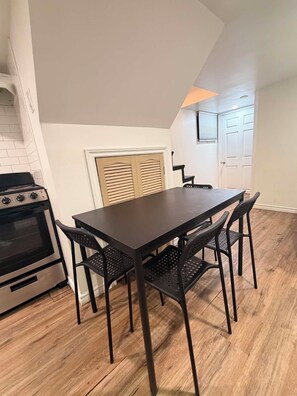 A kitchen with a dark wooden table and chairs, a stove, and a window with blinds. - Room to Stay in Niagara Falls (Niagara Falls)