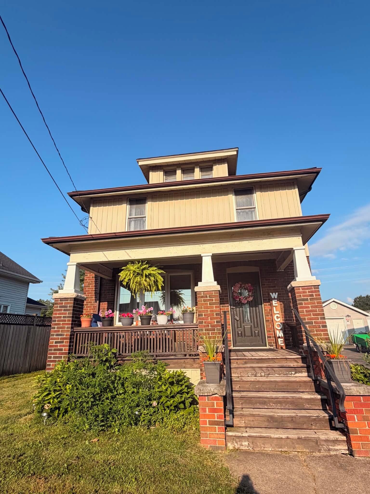A two-story house with a front porch, a welcome sign, and a garage.