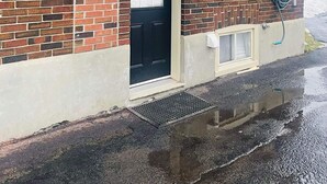 A brick building with a black awning over a door, a window, and a hose connected to a wall-mounted electrical box. - Room to Stay in Niagara Falls (Niagara Falls)